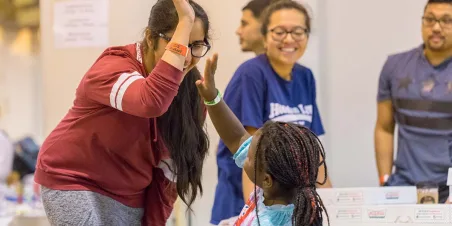 Support workers and volunteers play with a young girl at a shelter Implementation of Salesforce